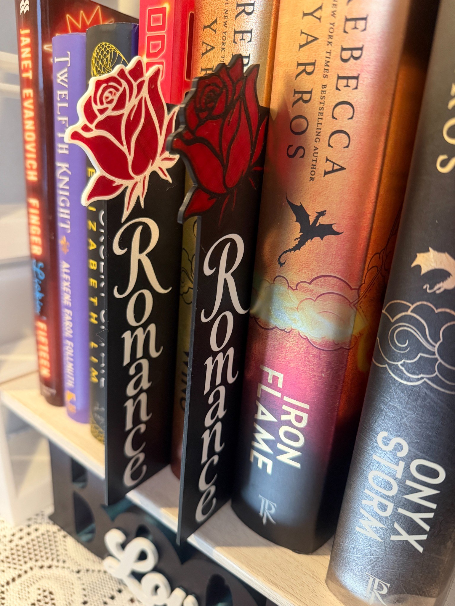 Rose-topped Romance genre signs displayed between books